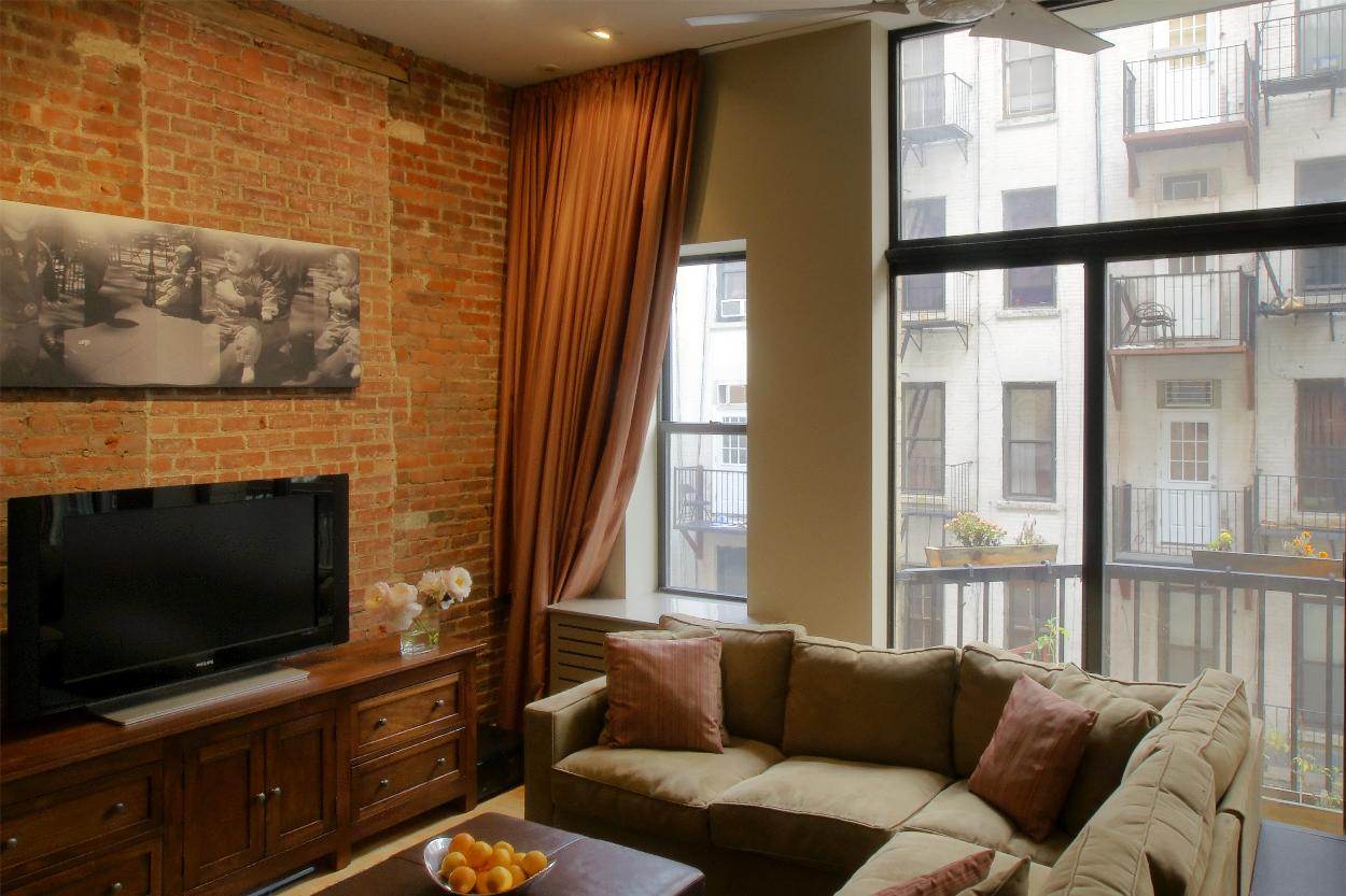 2nd Level Living Room with floor to ceiling windows and exposed brick wall
